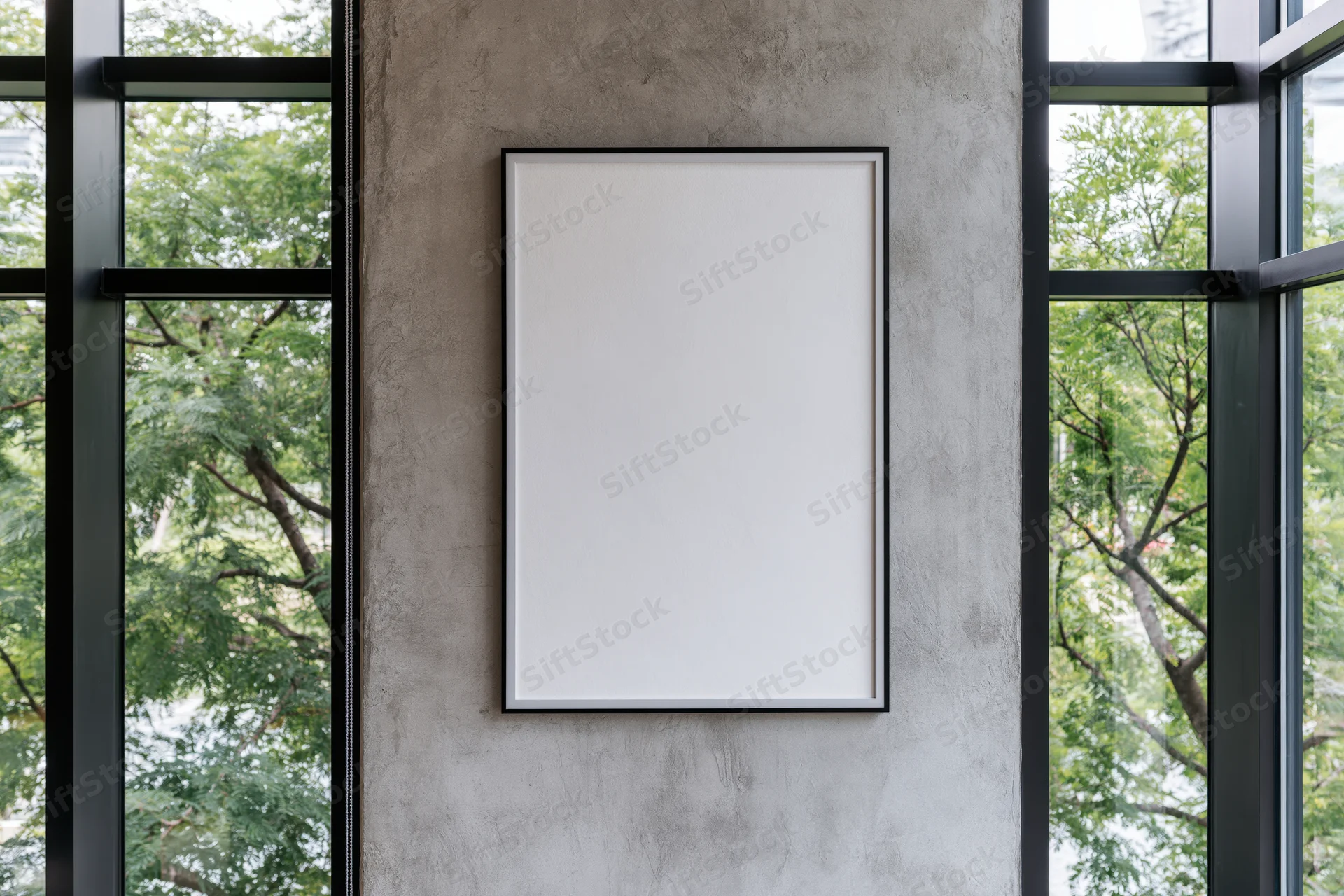 Blank white poster frame mounted on a concrete wall between glass windows in a modern interior