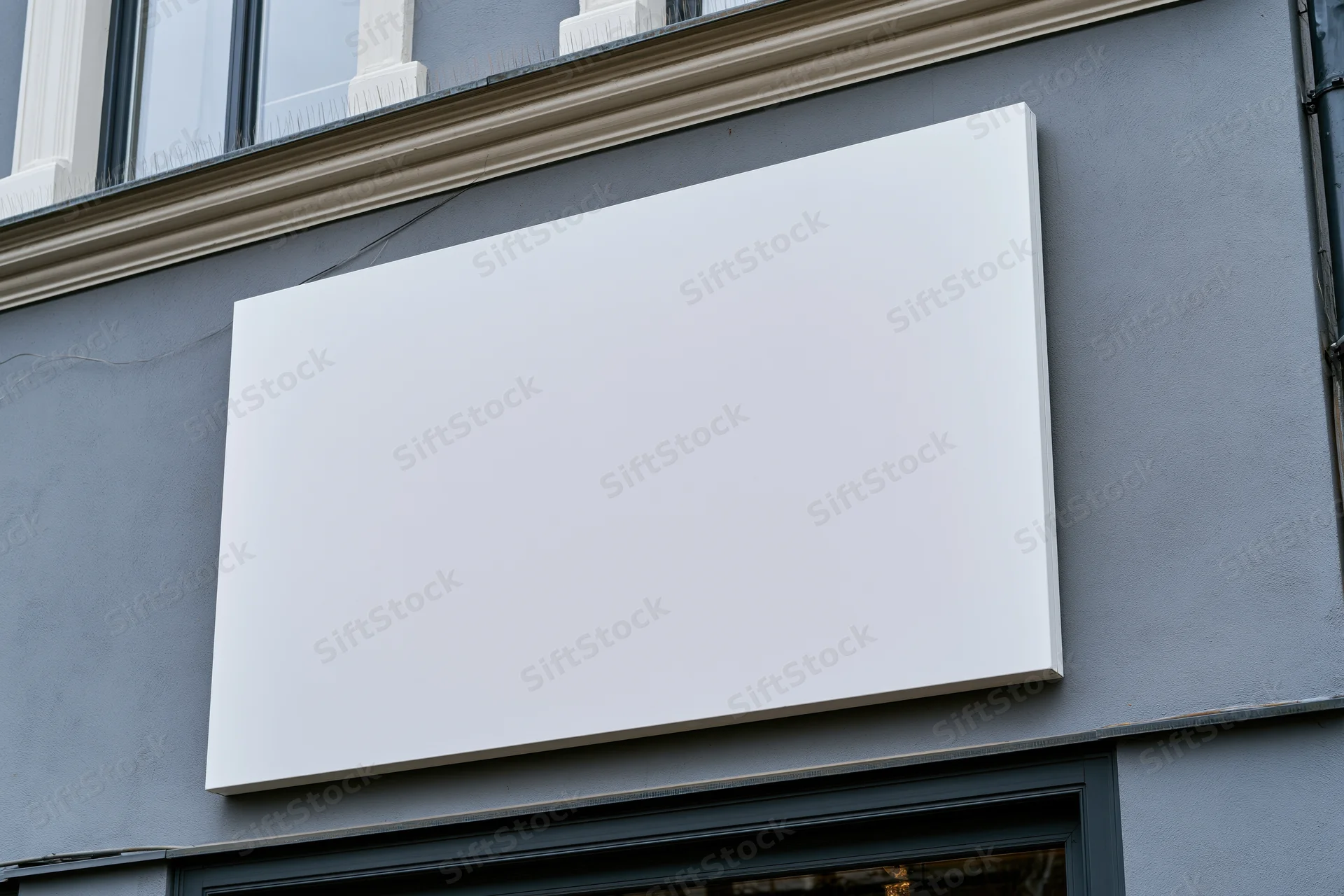 Blank white rectangular sign mounted on grey building facade above shop window