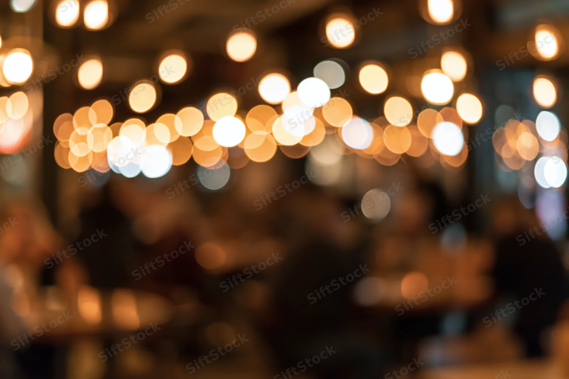 Blurred interior of a restaurant with warm bokeh lights and people dining at tables