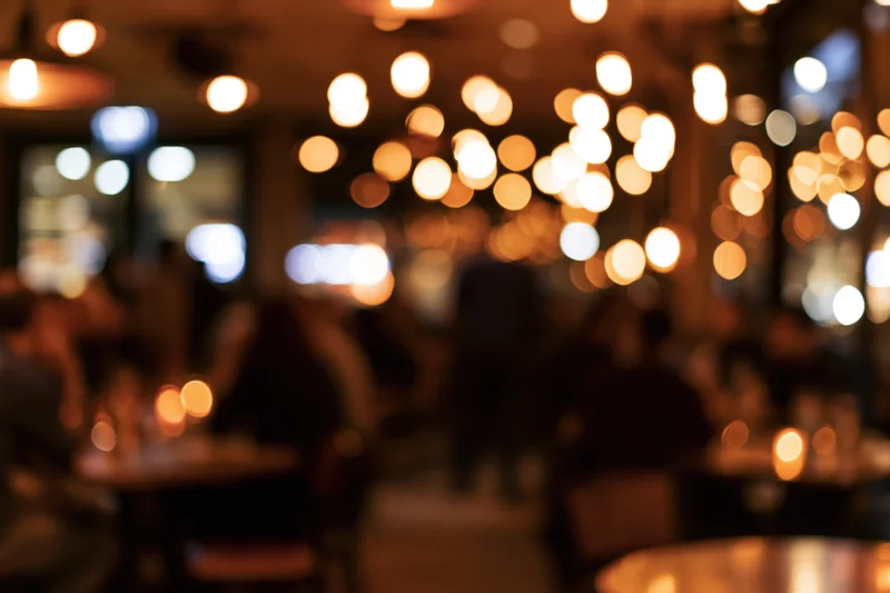 Blurred interior of a restaurant with warm bokeh lights and people dining at tables