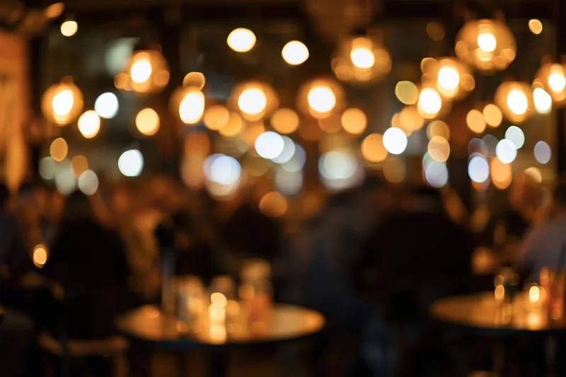 Blurred interior of a dimly lit restaurant with warm bokeh lights and people at tables