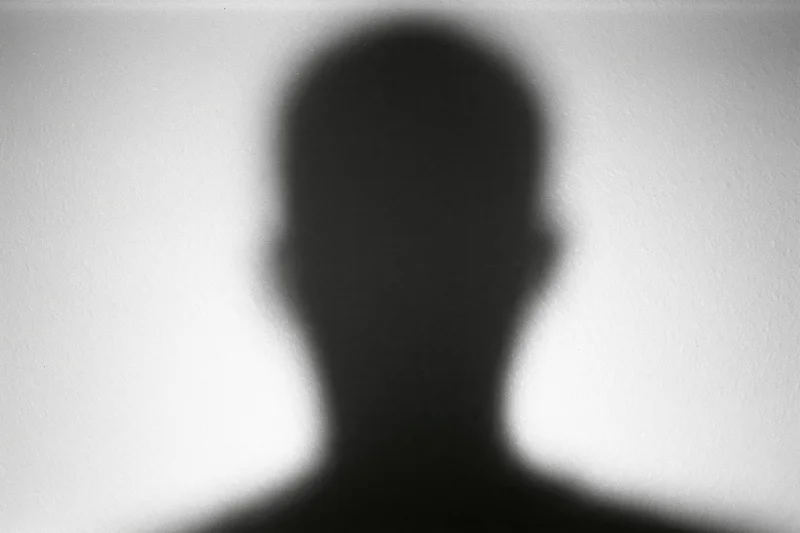 Blurred silhouette of a person's head and shoulders cast on a light wall