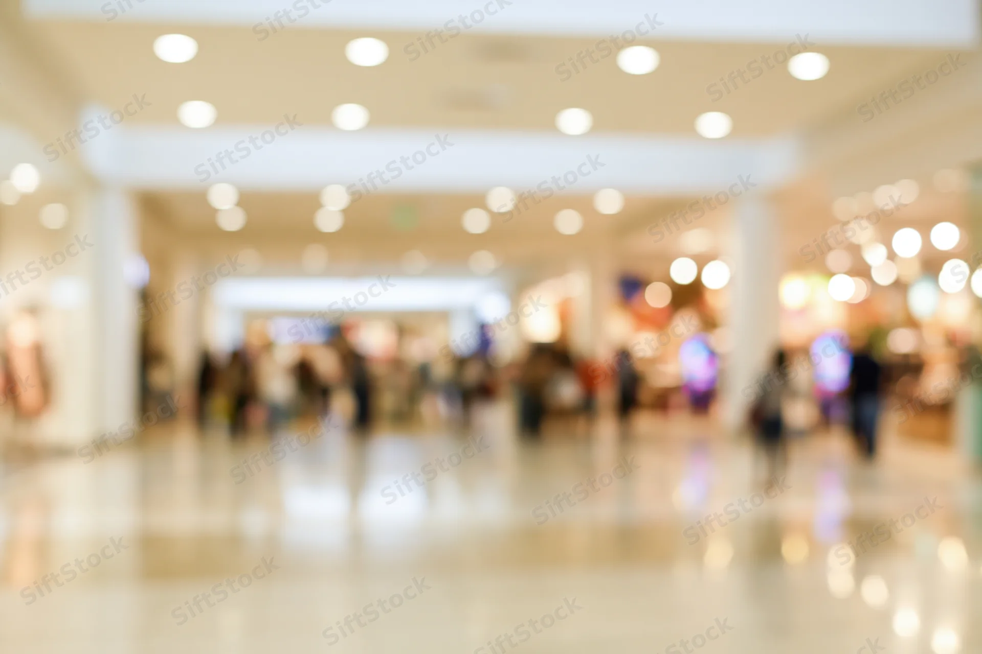 Blurred interior of a busy shopping mall corridor with people and lights