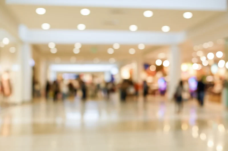 Blurred interior of a busy shopping mall corridor with people and lights
