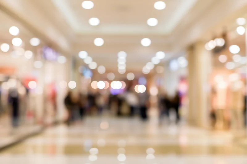 Blurred interior of a busy shopping mall corridor with bokeh lights and people walking