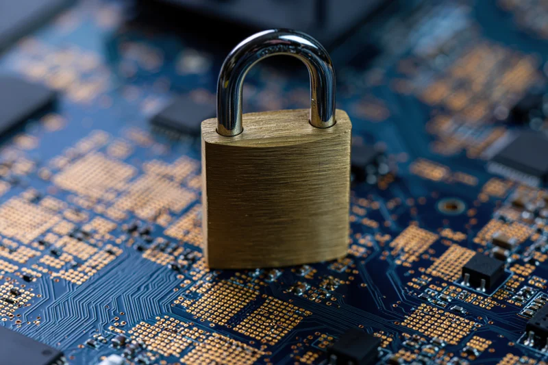 Brass padlock resting on a dark blue circuit board with visible electronic components
