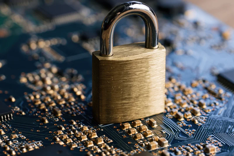 Brass padlock standing upright on a dark blue circuit board