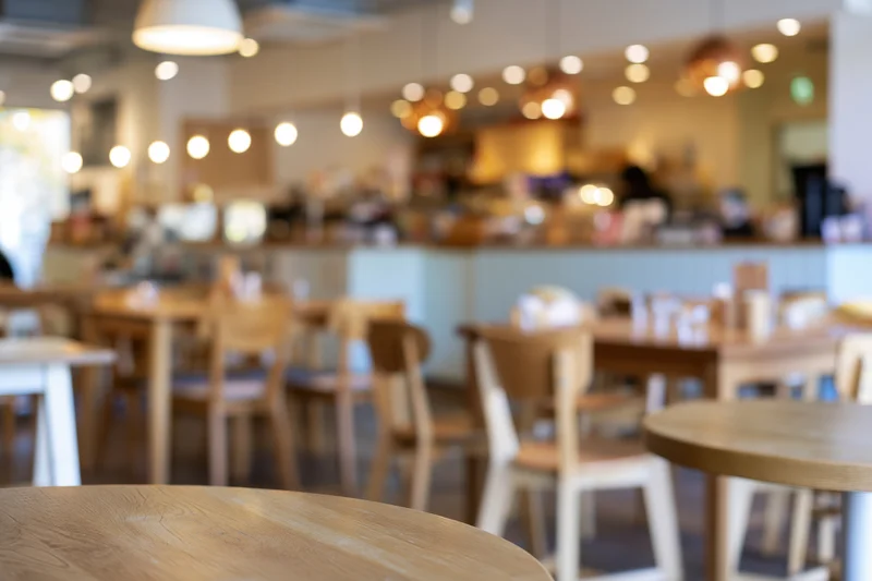 Modern cafe interior with wooden tables and chairs under warm pendant lighting