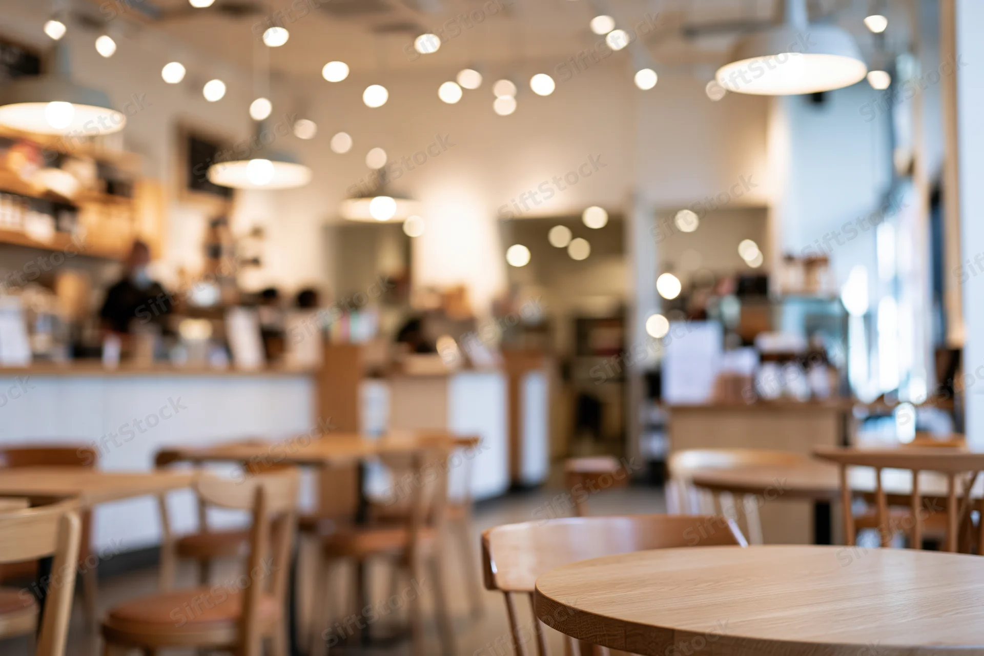Modern cafe interior with wooden tables and chairs under warm pendant lighting