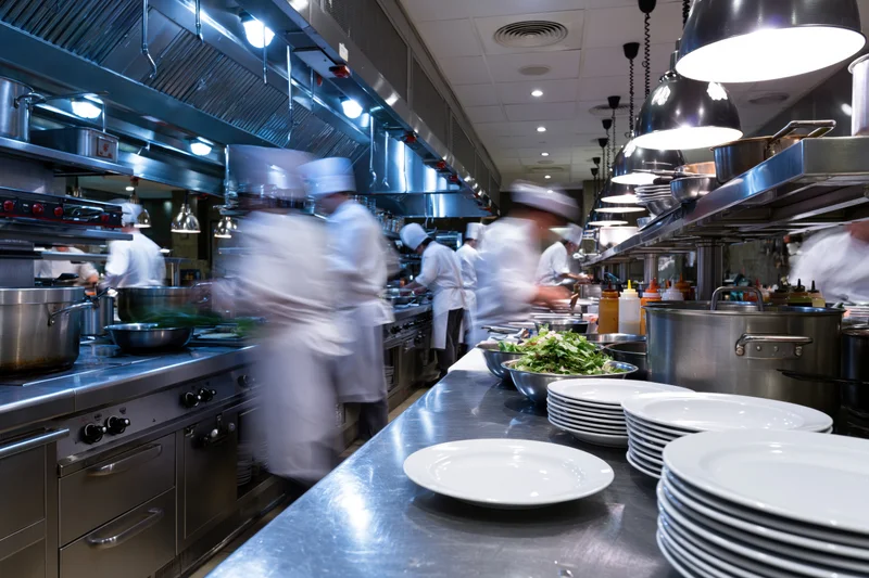 Chefs cooking in a busy commercial restaurant kitchen during dinner service