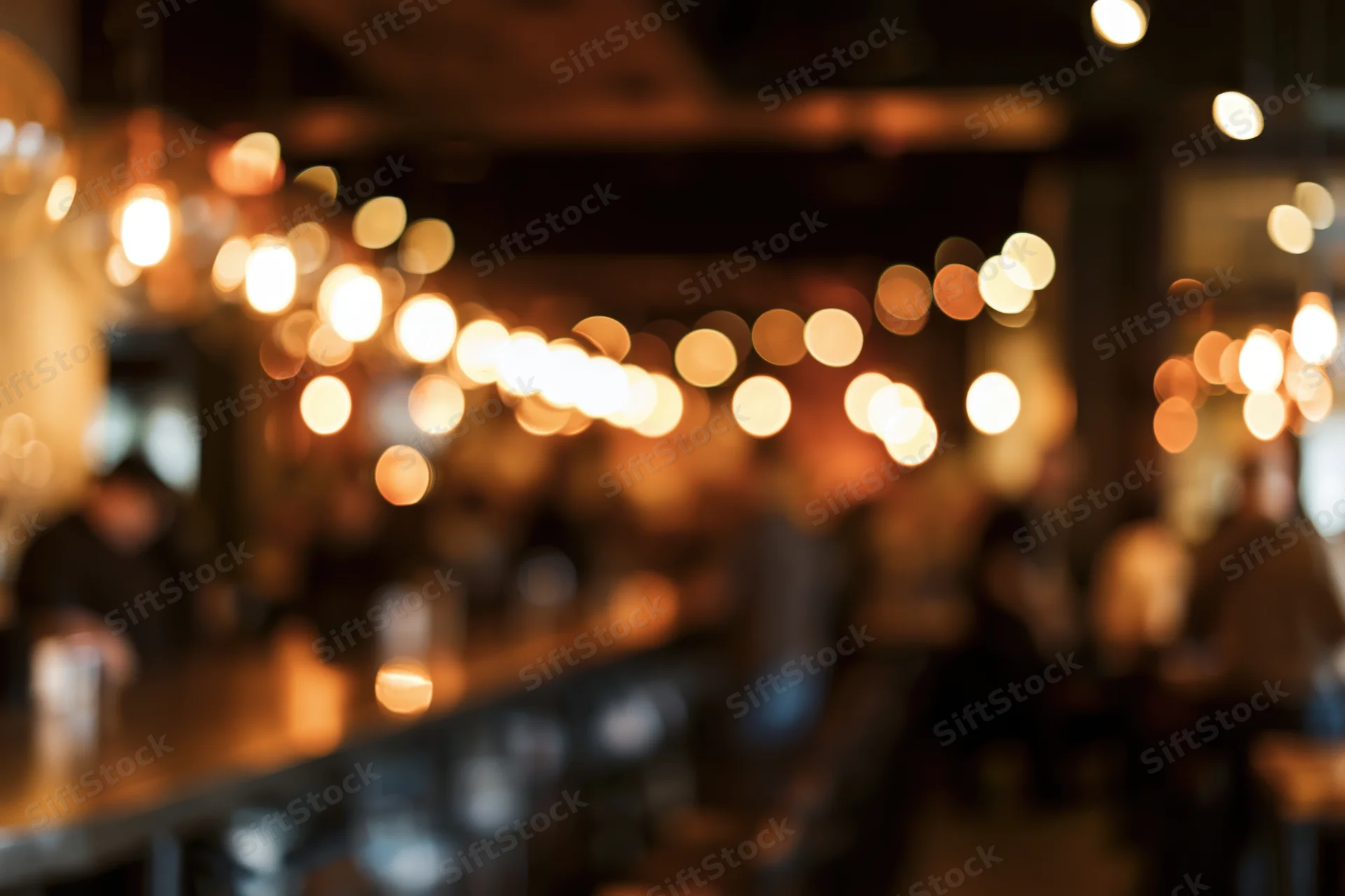 Blurred interior of a warm restaurant with hanging pendant lights and soft glow
