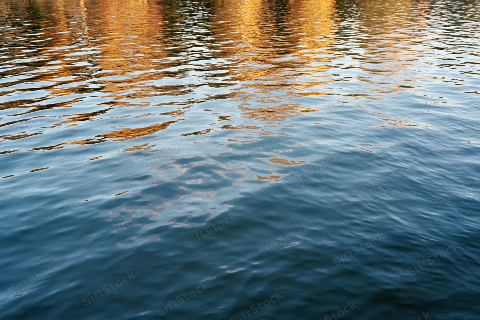 Calm lake surface with gentle ripples reflecting autumn colors