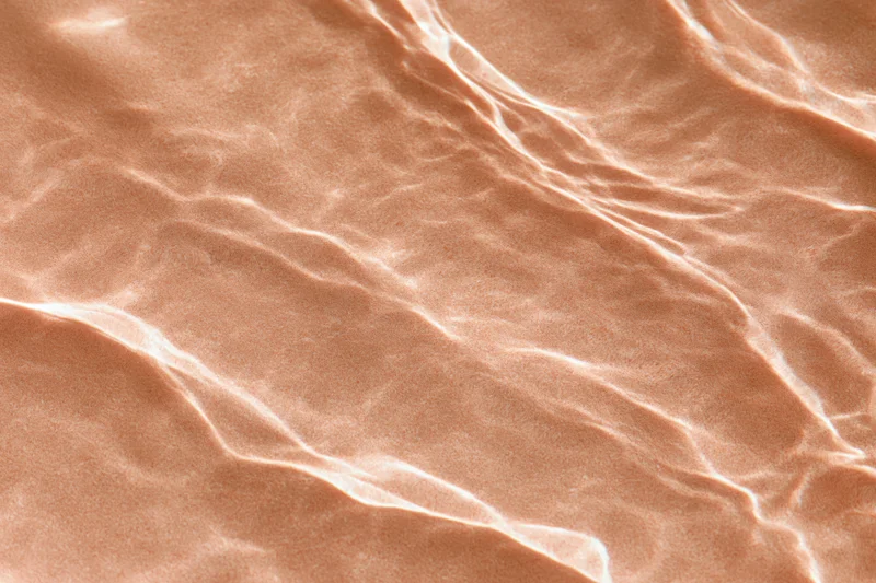 Rippling water surface with light reflections over sandy bottom