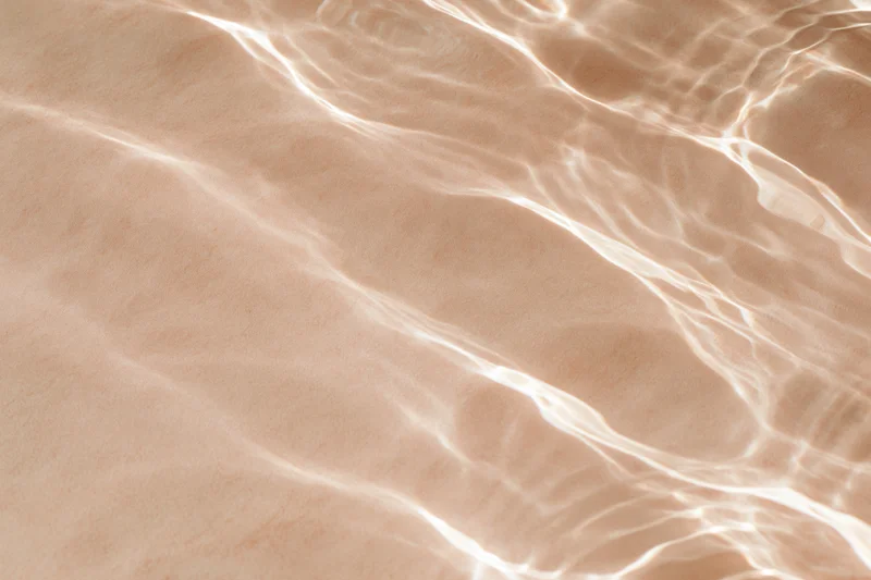 Rippling water surface with light reflections over sandy bottom