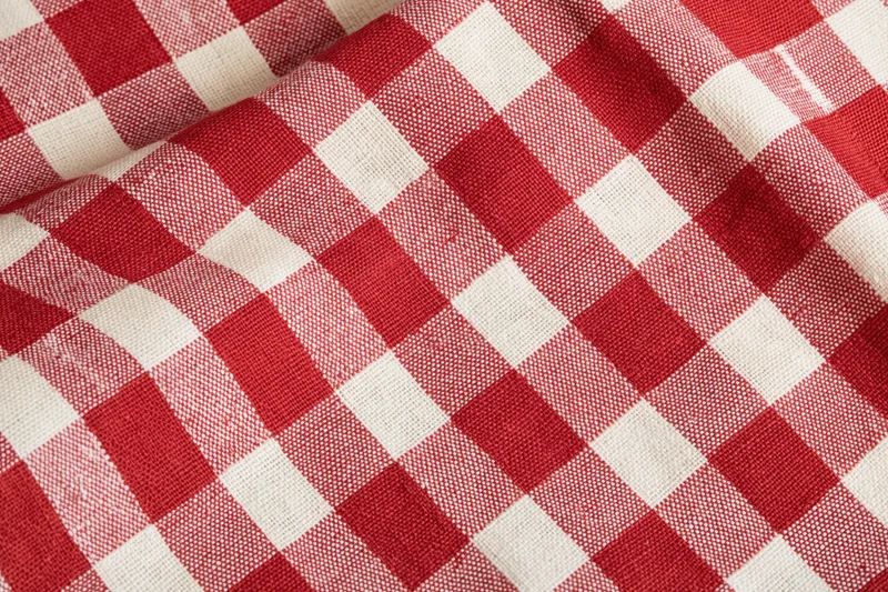 Close-up of red and white gingham cotton tablecloth with visible weave and folds