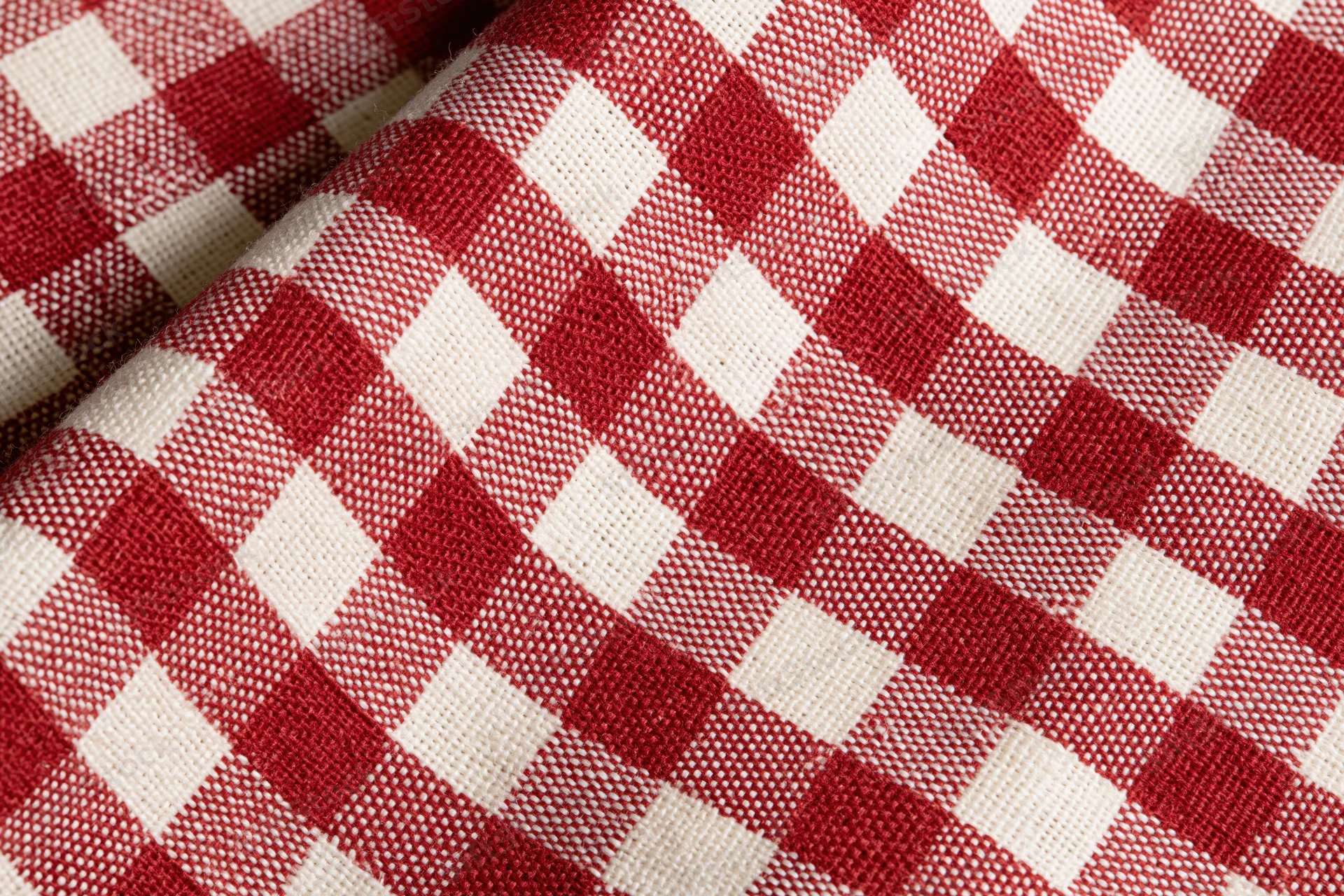 Close-up of red and white gingham cotton tablecloth laid flat showing woven texture and checkered pattern