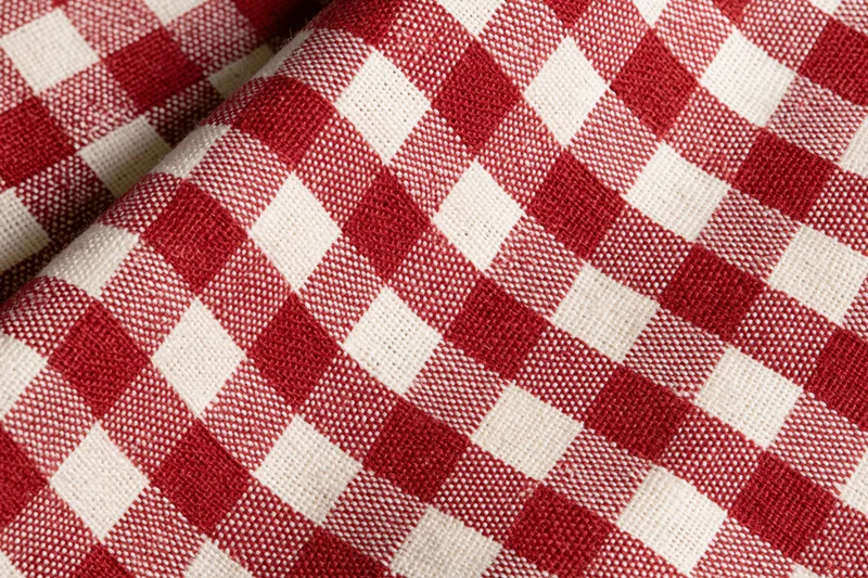 Close-up of red and white gingham cotton tablecloth laid flat showing woven texture and checkered pattern