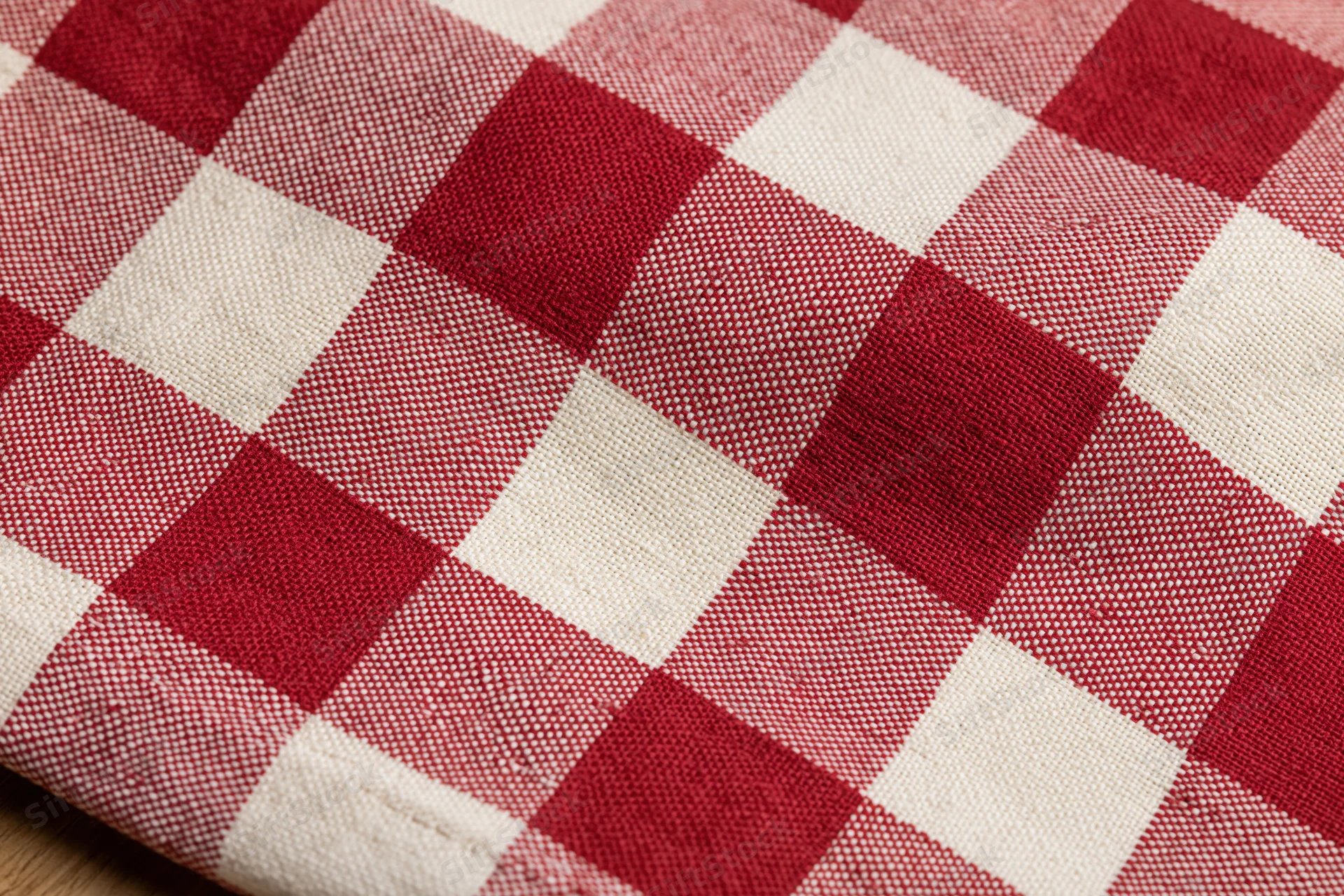 Close-up of red and white gingham cotton tablecloth laid flat on a surface