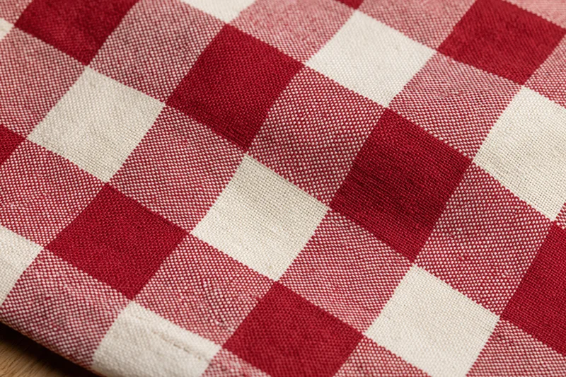 Close-up of red and white gingham cotton tablecloth laid flat on a surface