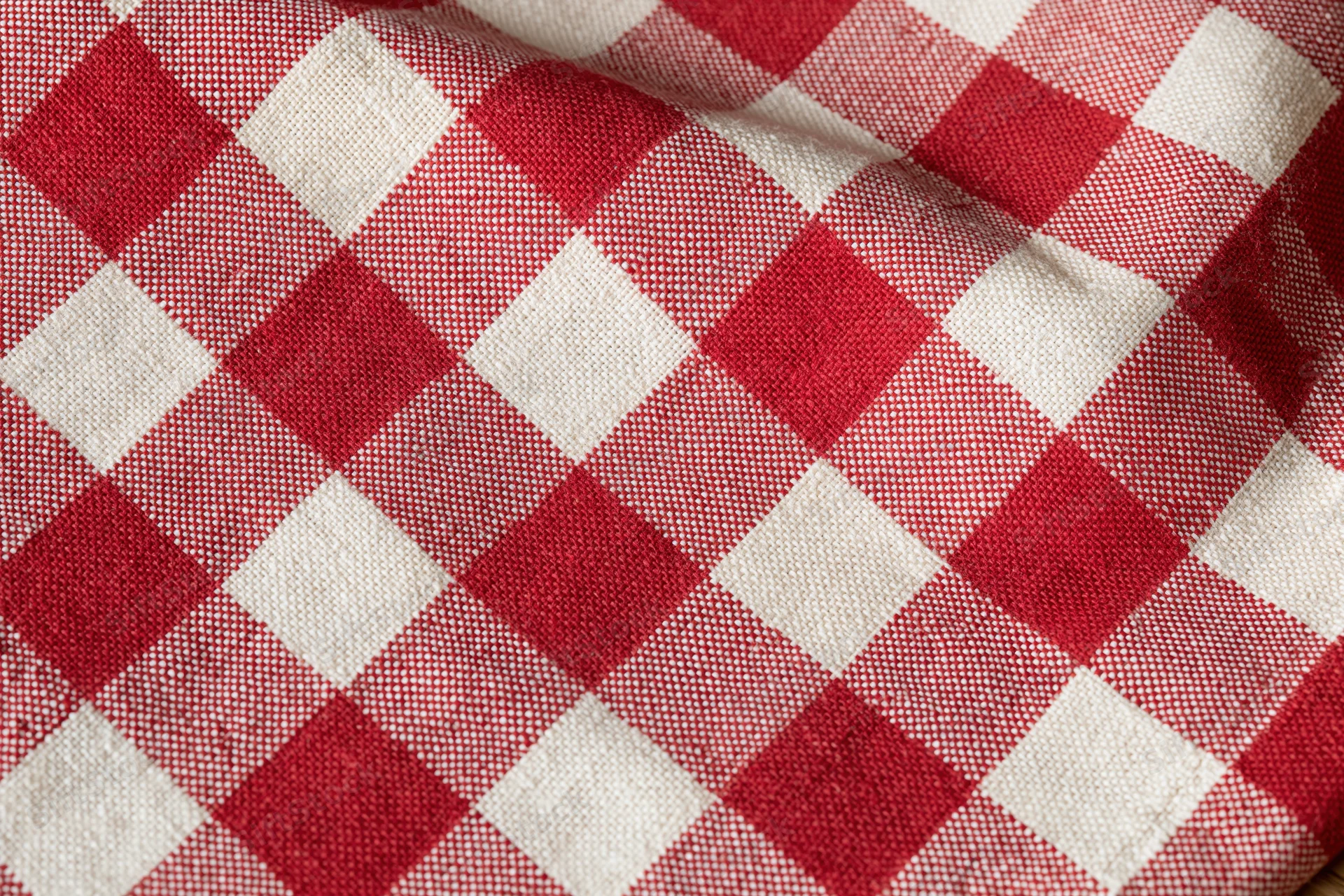 Close-up of red and white gingham cotton tablecloth laid flat showing woven texture and checkered pattern