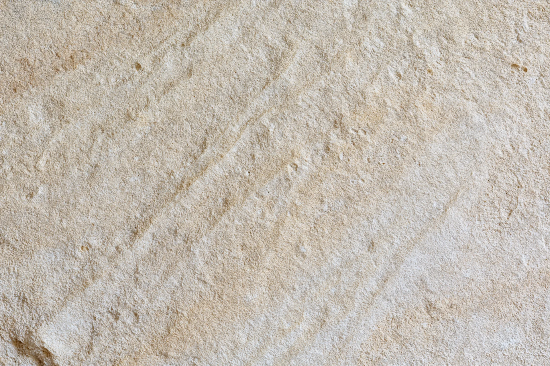 Close-up of rough sandstone surface with natural texture and beige coloration