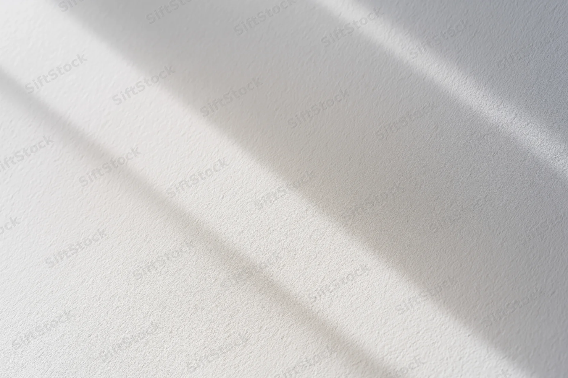Diagonal light and shadow on a white textured surface