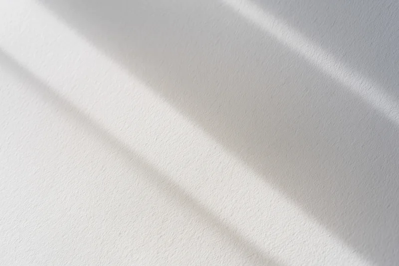 Diagonal light and shadow on a white textured surface