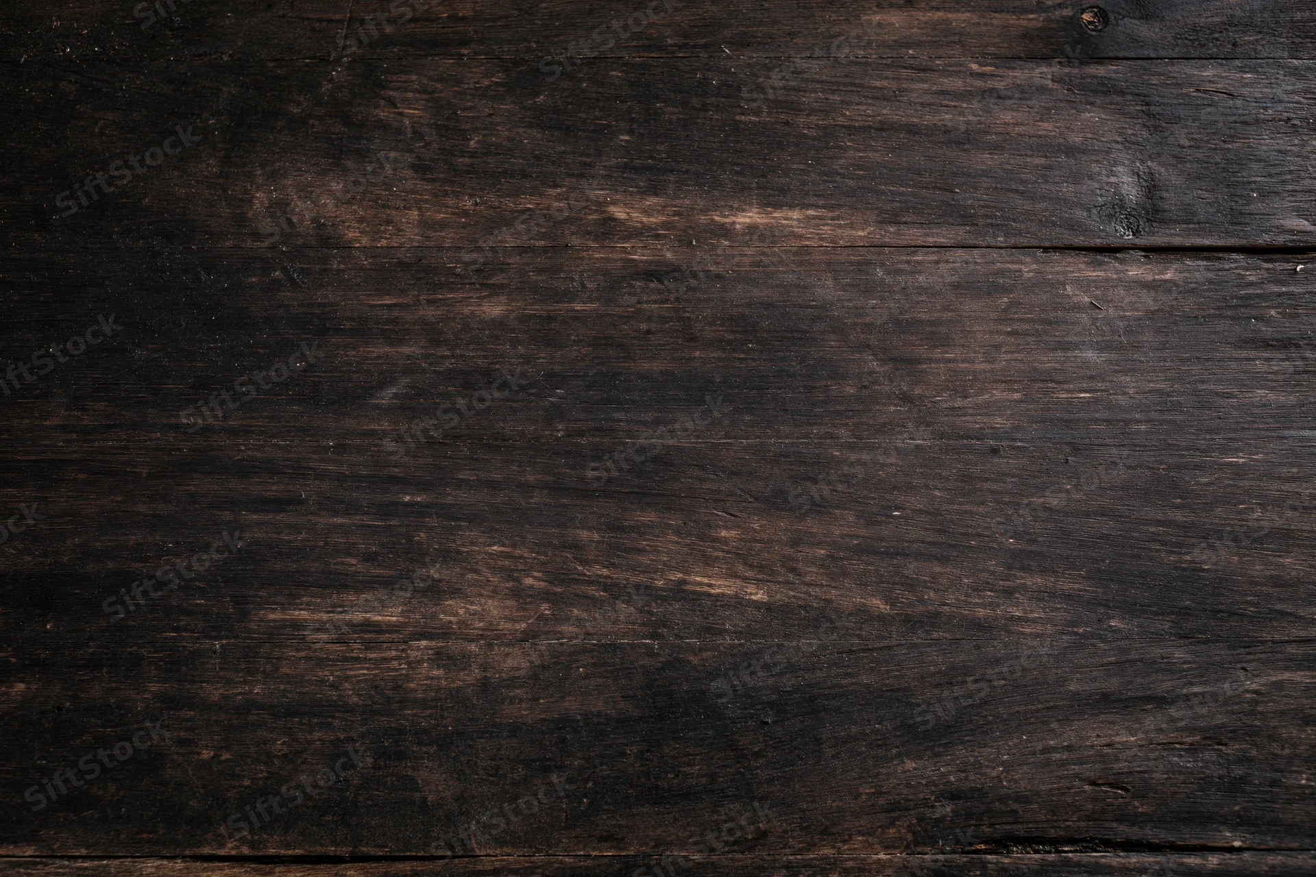 Close-up of dark aged wooden surface with visible grain and wear marks