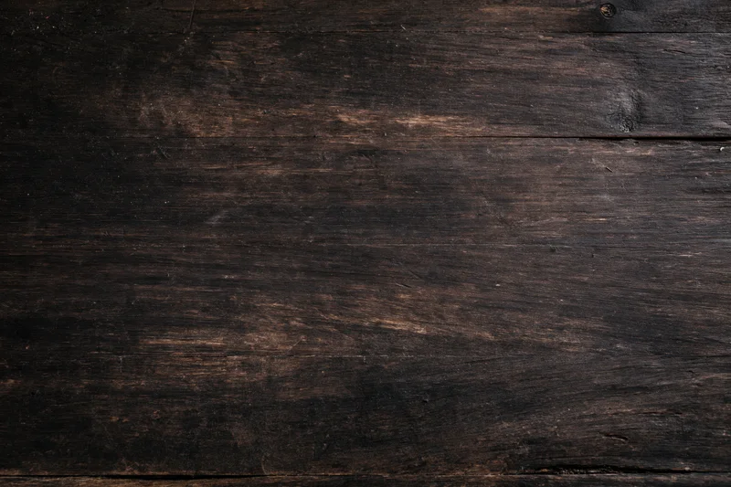 Close-up of dark aged wooden surface with visible grain and wear marks