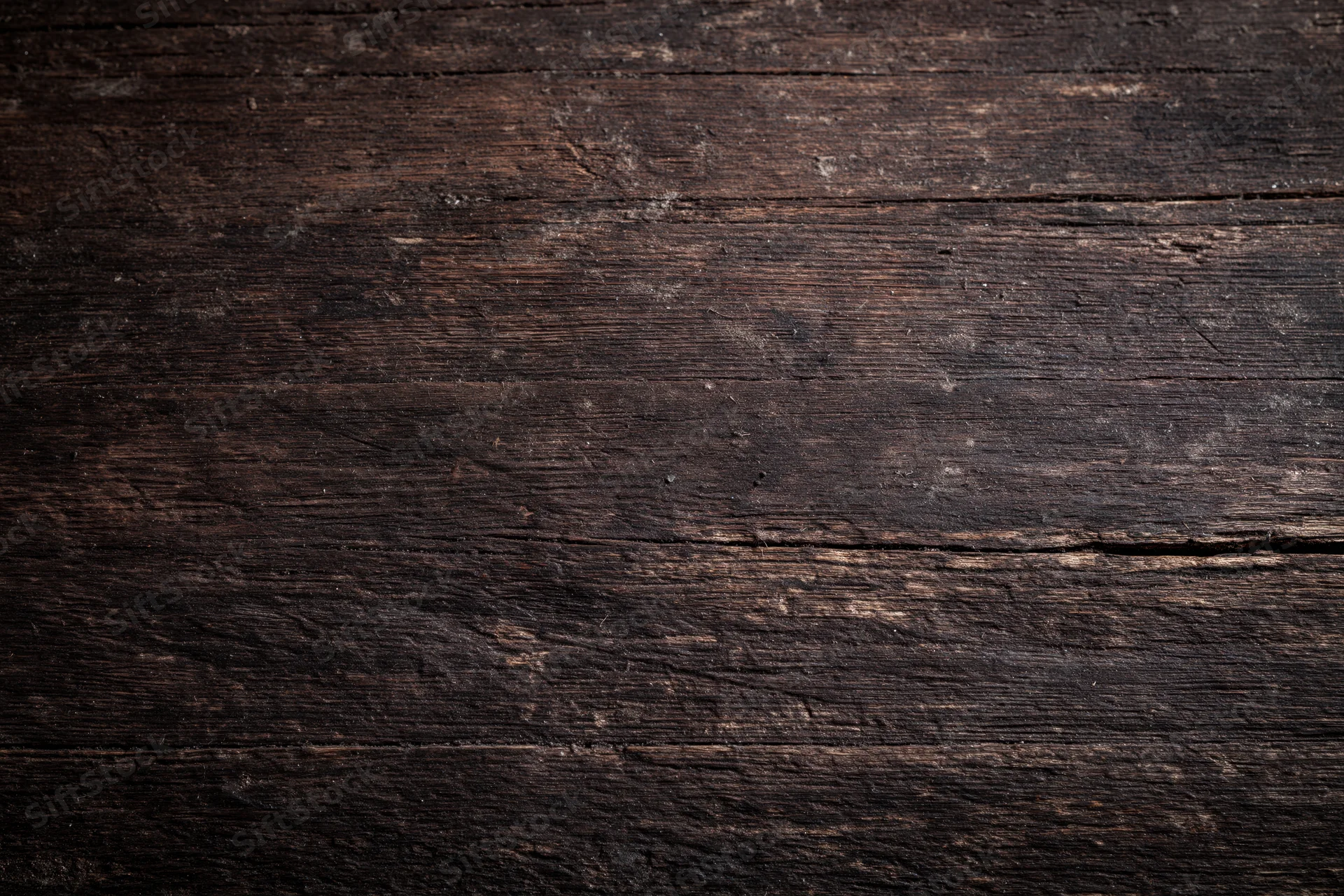 Close-up of dark aged wooden surface with visible grain and weathered texture