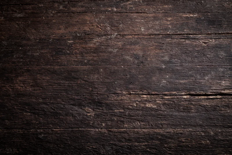 Close-up of dark aged wooden surface with visible grain and weathered texture