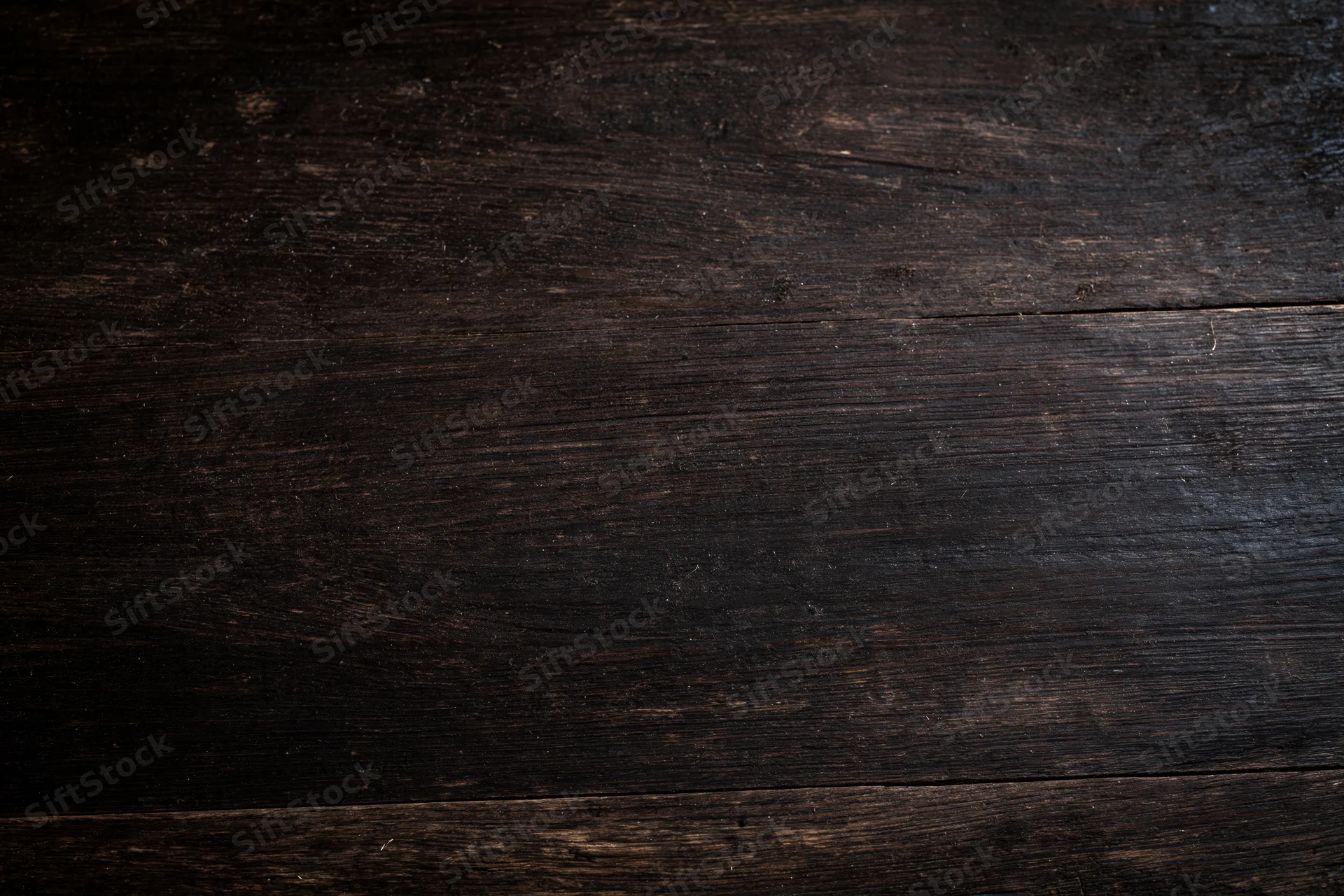 Close-up of dark aged wooden surface with visible grain and wear marks