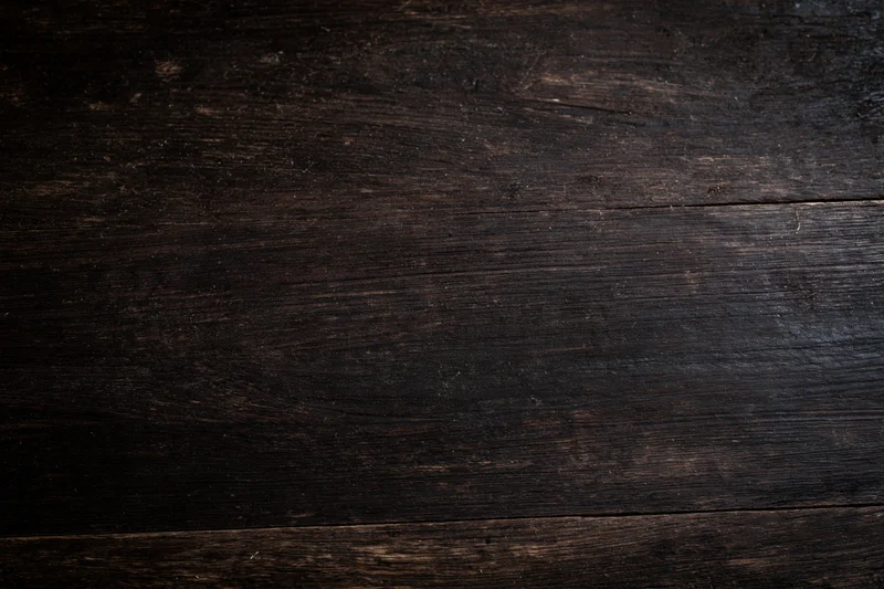 Close-up of dark aged wooden surface with visible grain and wear marks