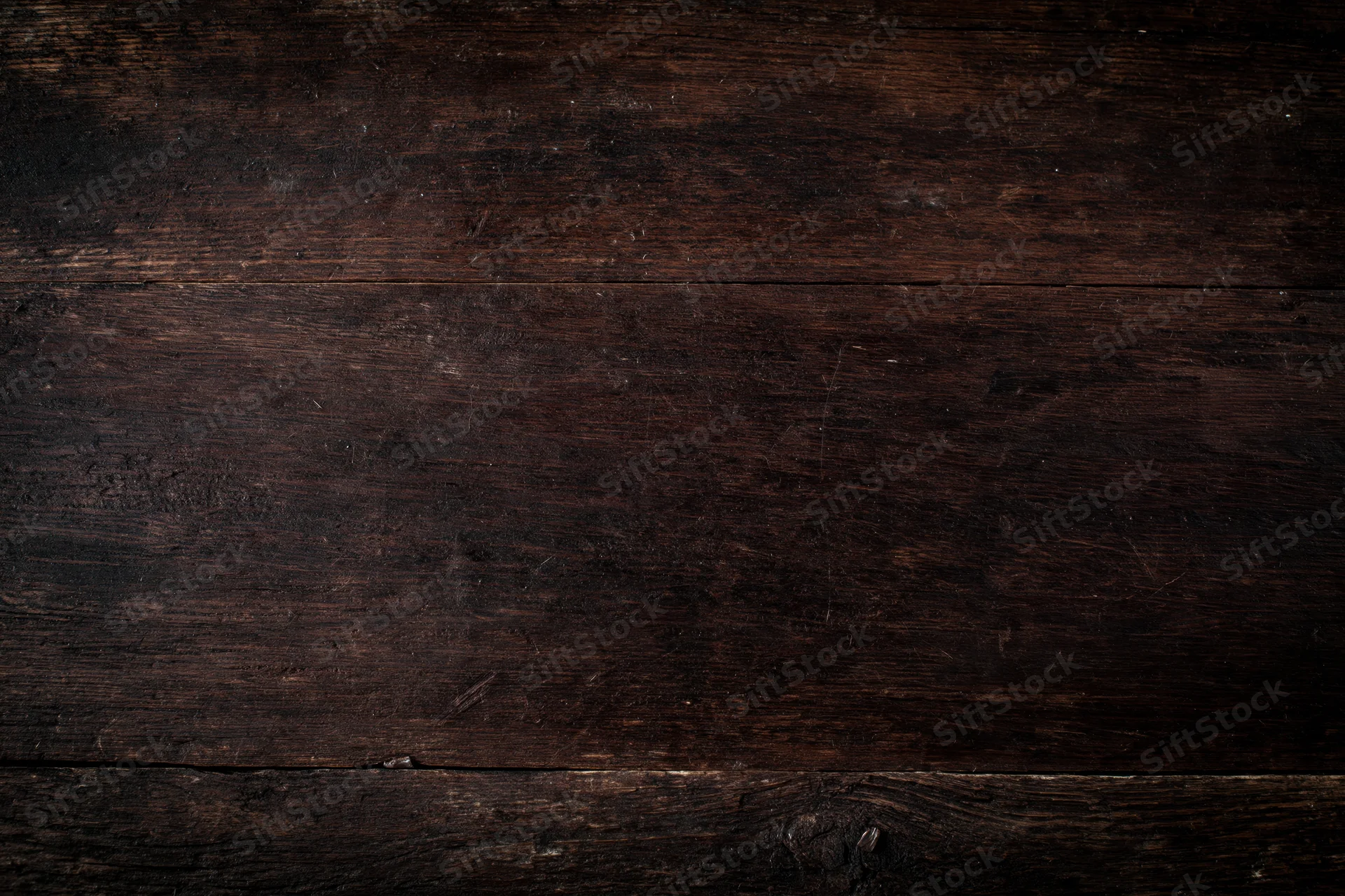 Close-up of dark aged wooden surface with visible grain and wear marks