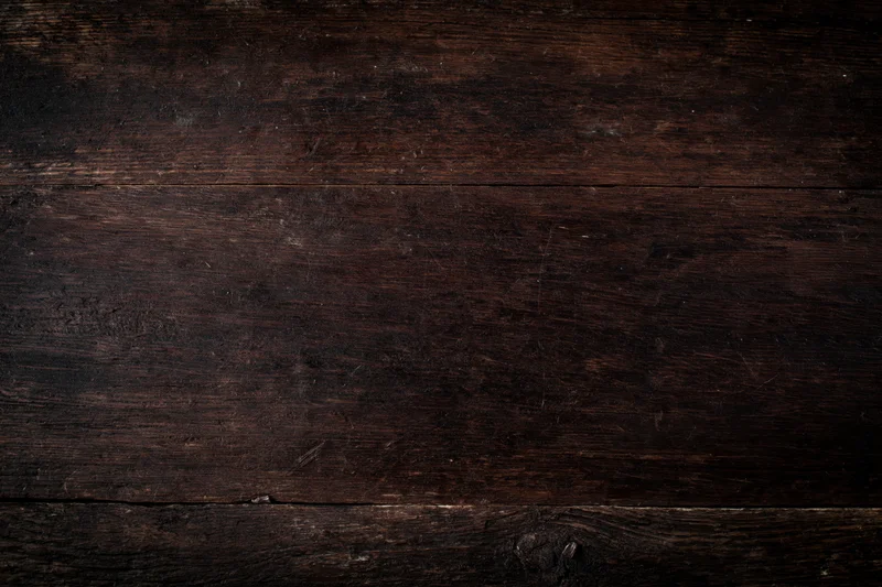 Close-up of dark aged wooden surface with visible grain and wear marks