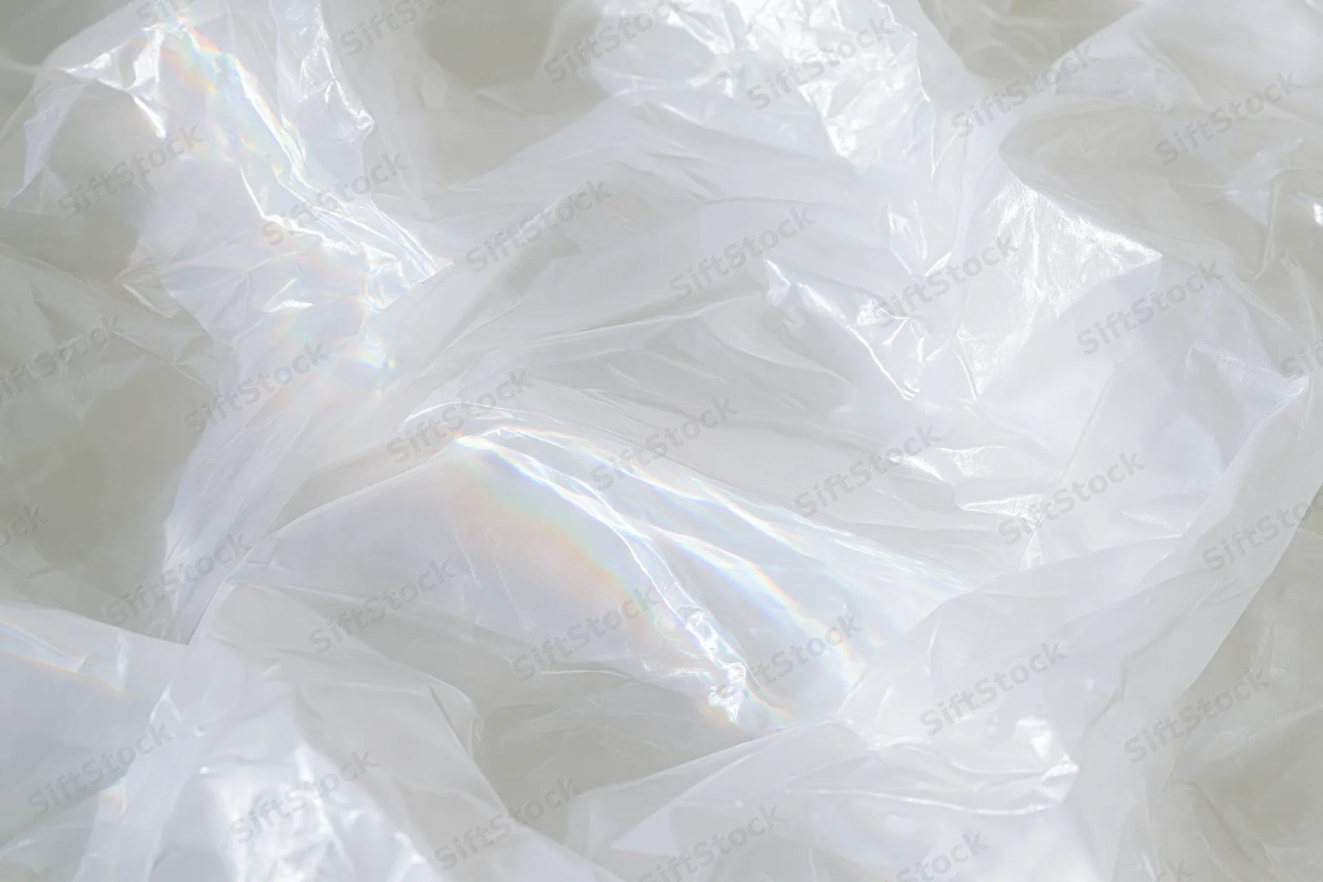 Crumpled translucent white plastic sheet with iridescent sheen and folds forming a textured surface