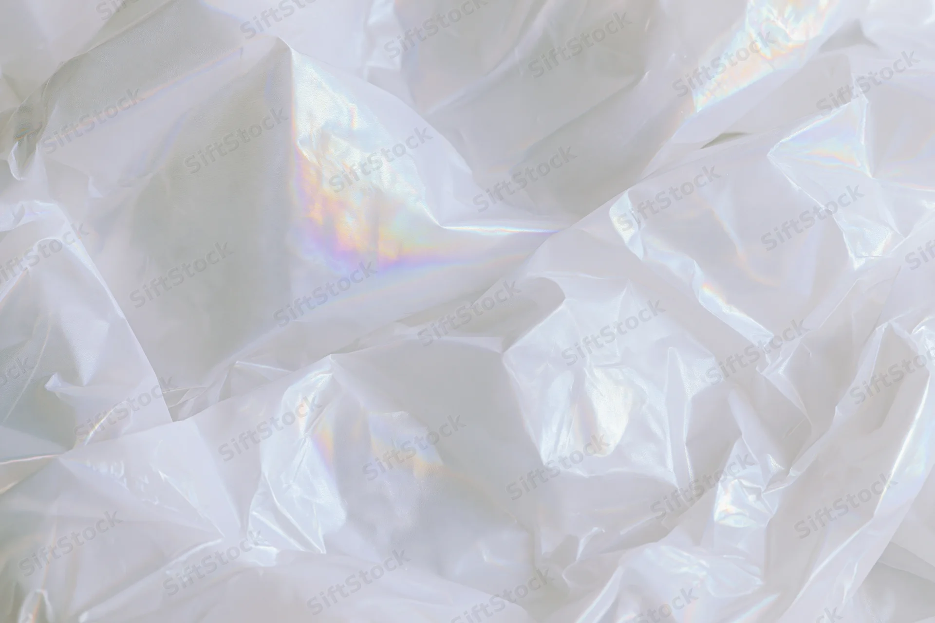 Crumpled translucent white plastic sheet with iridescent sheen in flat lay view