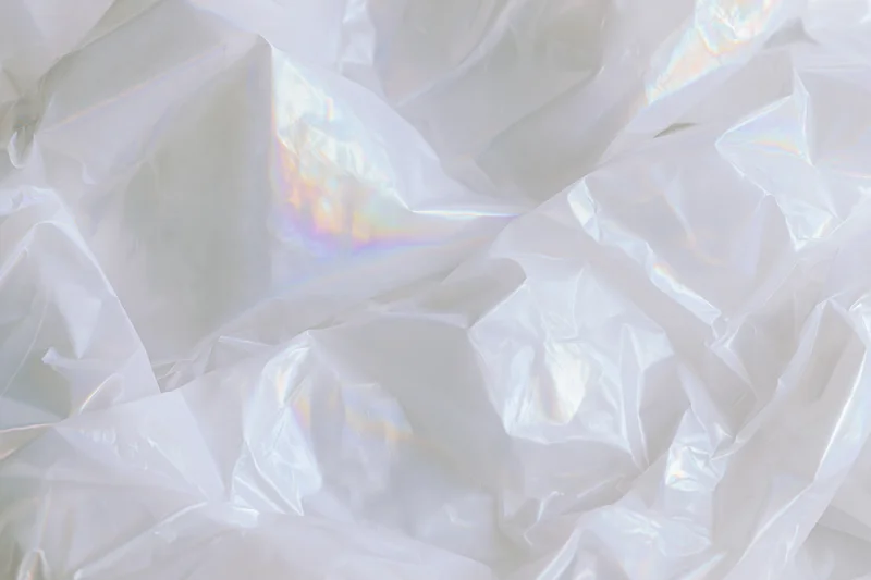 Crumpled translucent white plastic sheet with iridescent sheen in flat lay view