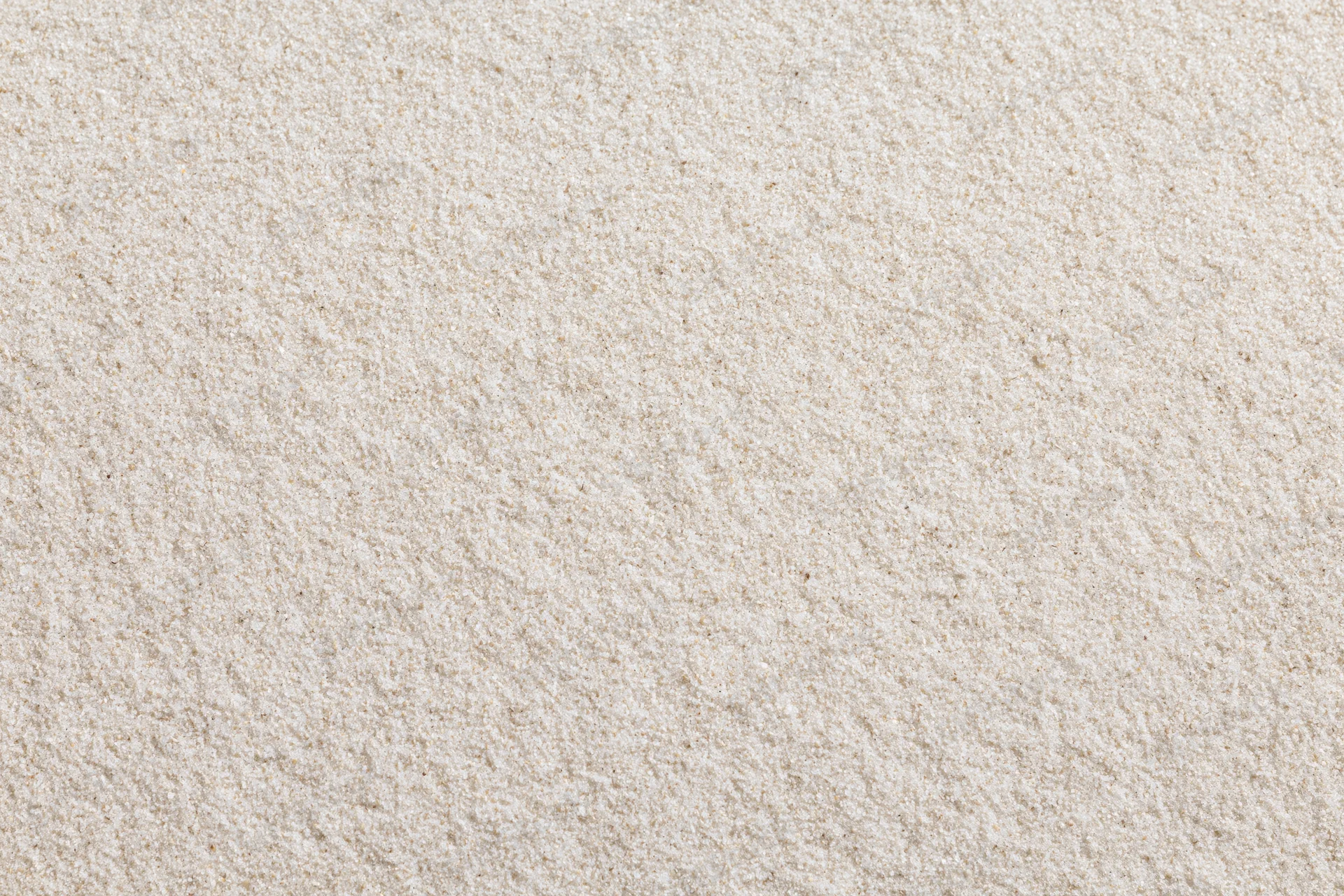 Close-up of fine dry beach sand filling the frame as a textured surface