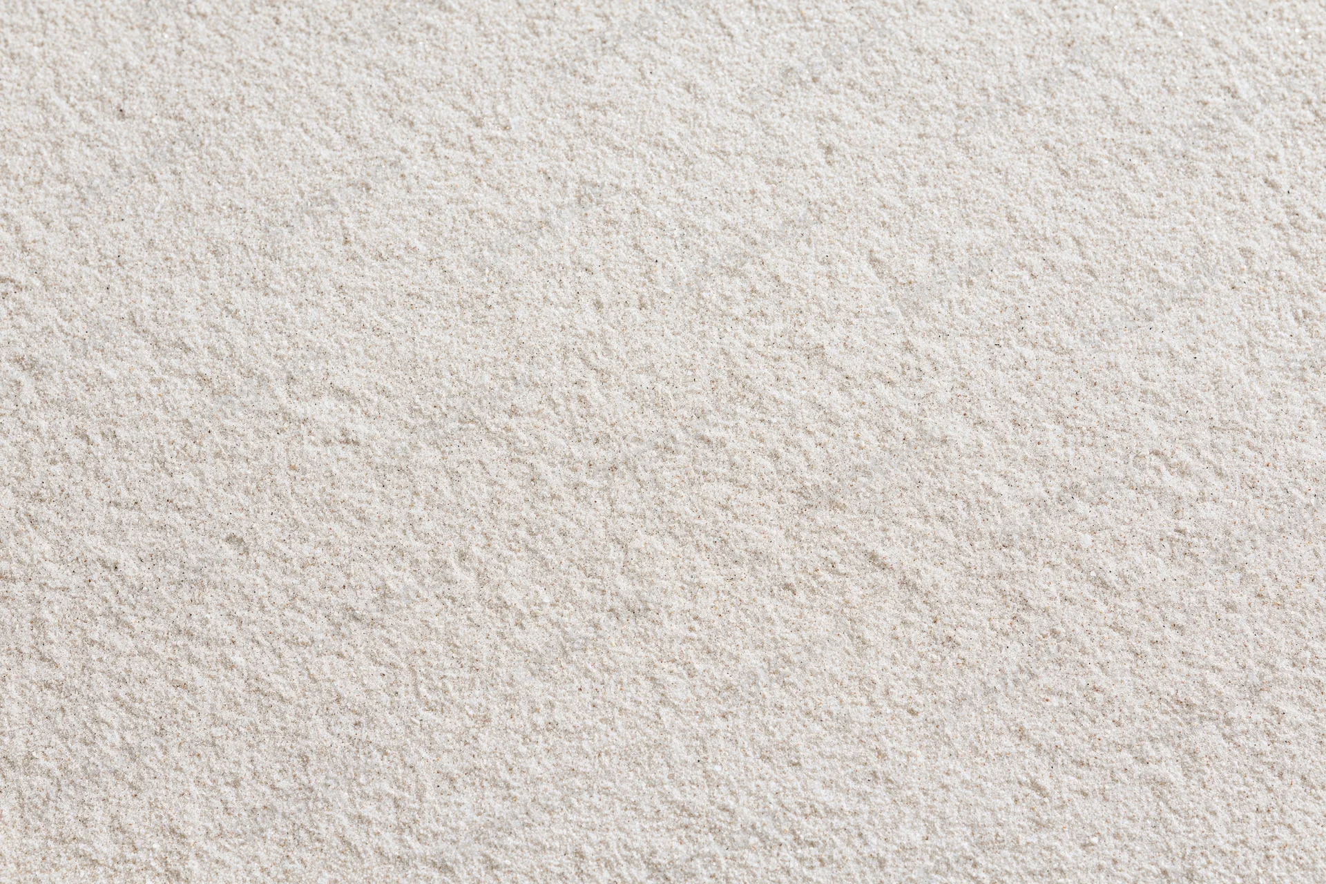 Close-up of fine dry beach sand filling the frame as a textured surface