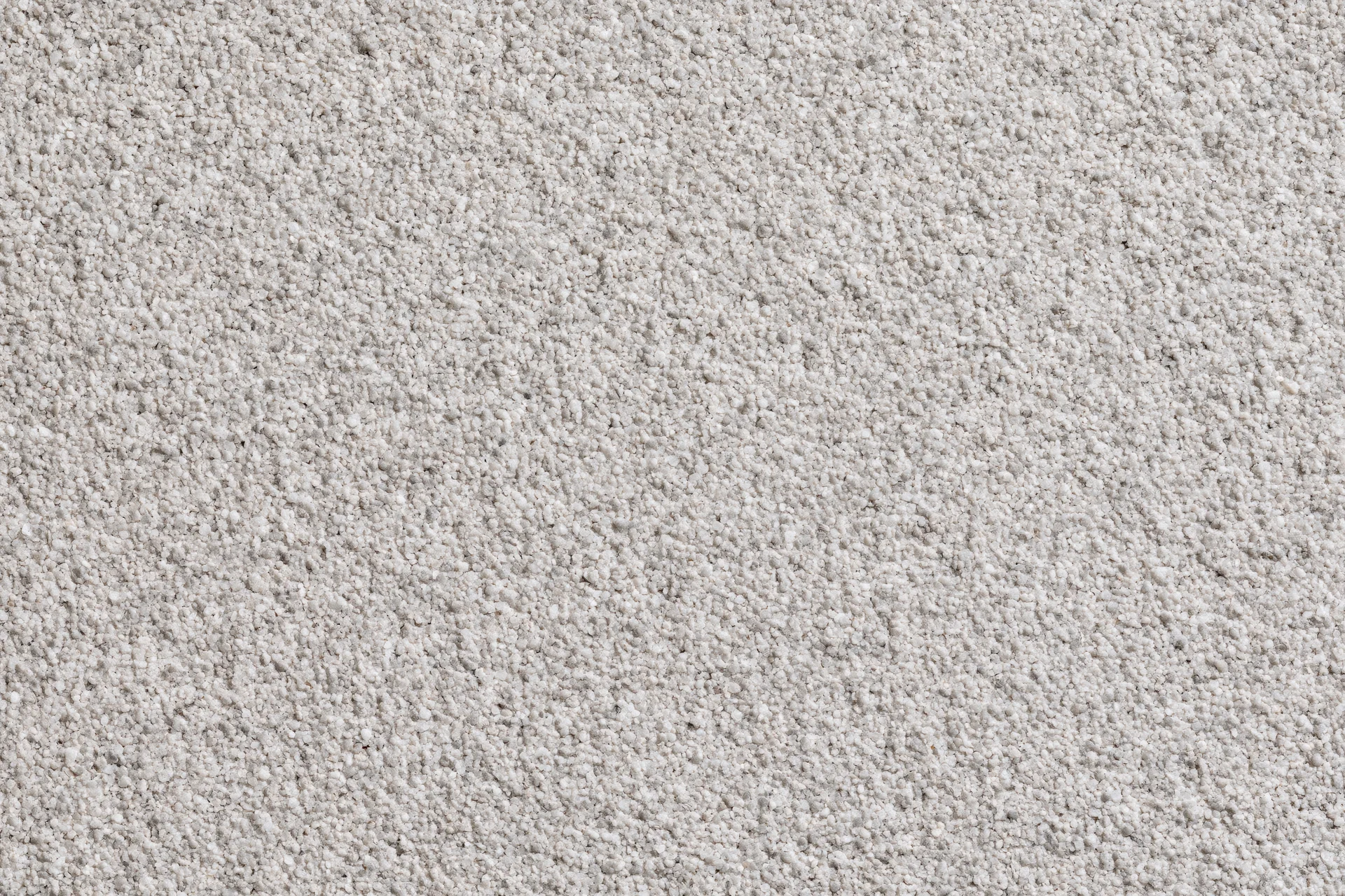 Close-up of beige carpet texture showing fine granular surface and dense pile for interior flooring