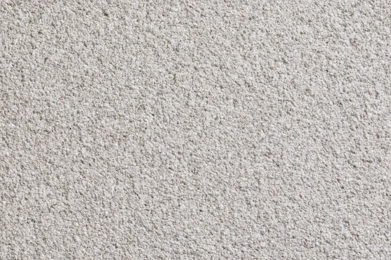 Close-up of beige carpet texture showing fine granular surface and dense pile for interior flooring