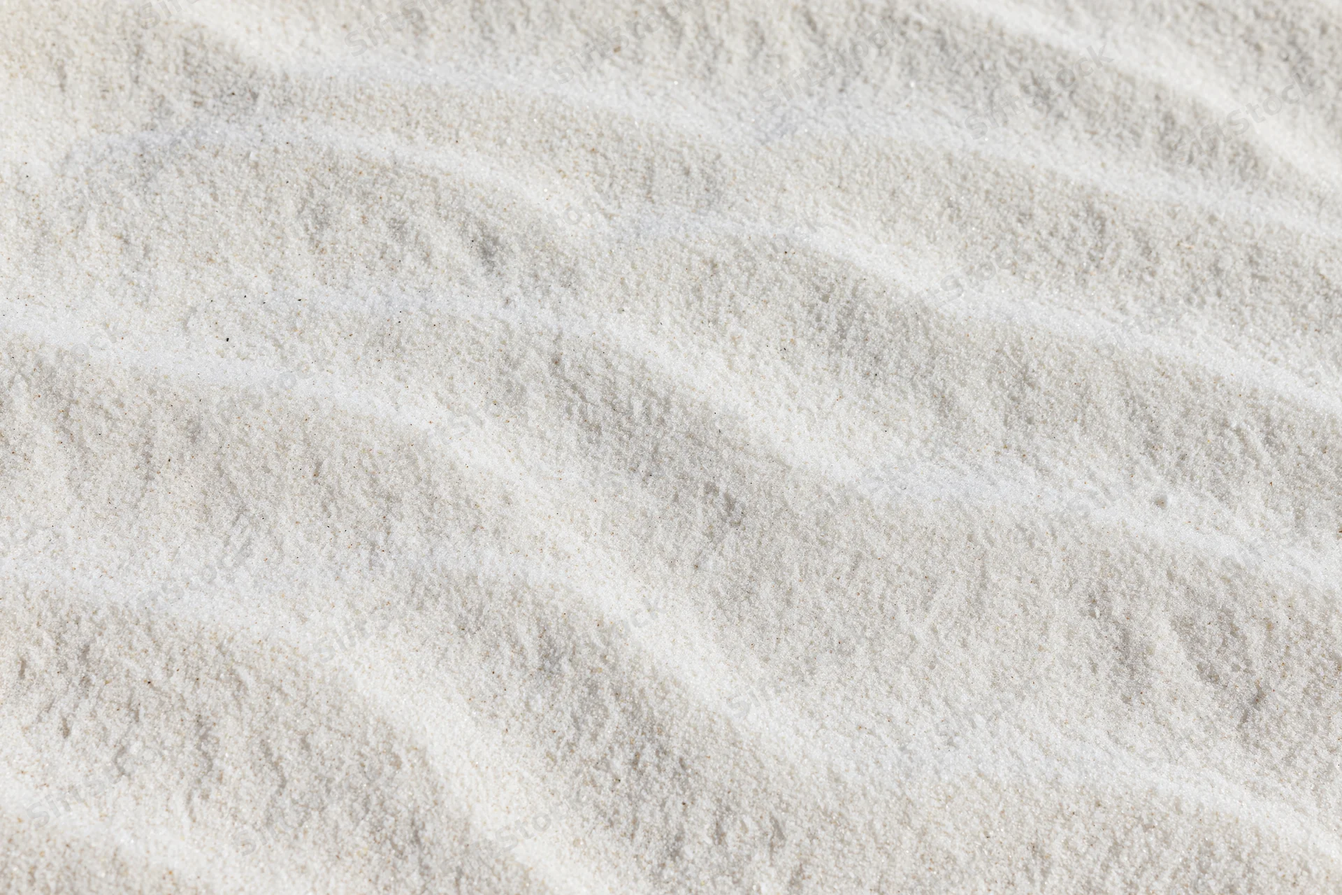 Close-up of fine white beach sand with wind-formed ripples in a flat lay arrangement