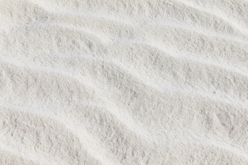 Close-up of fine white beach sand with wind-formed ripples in a flat lay arrangement