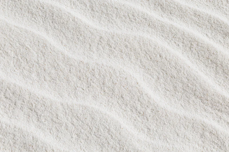 Close-up of fine white beach sand with wind-formed ripples in a flat lay arrangement