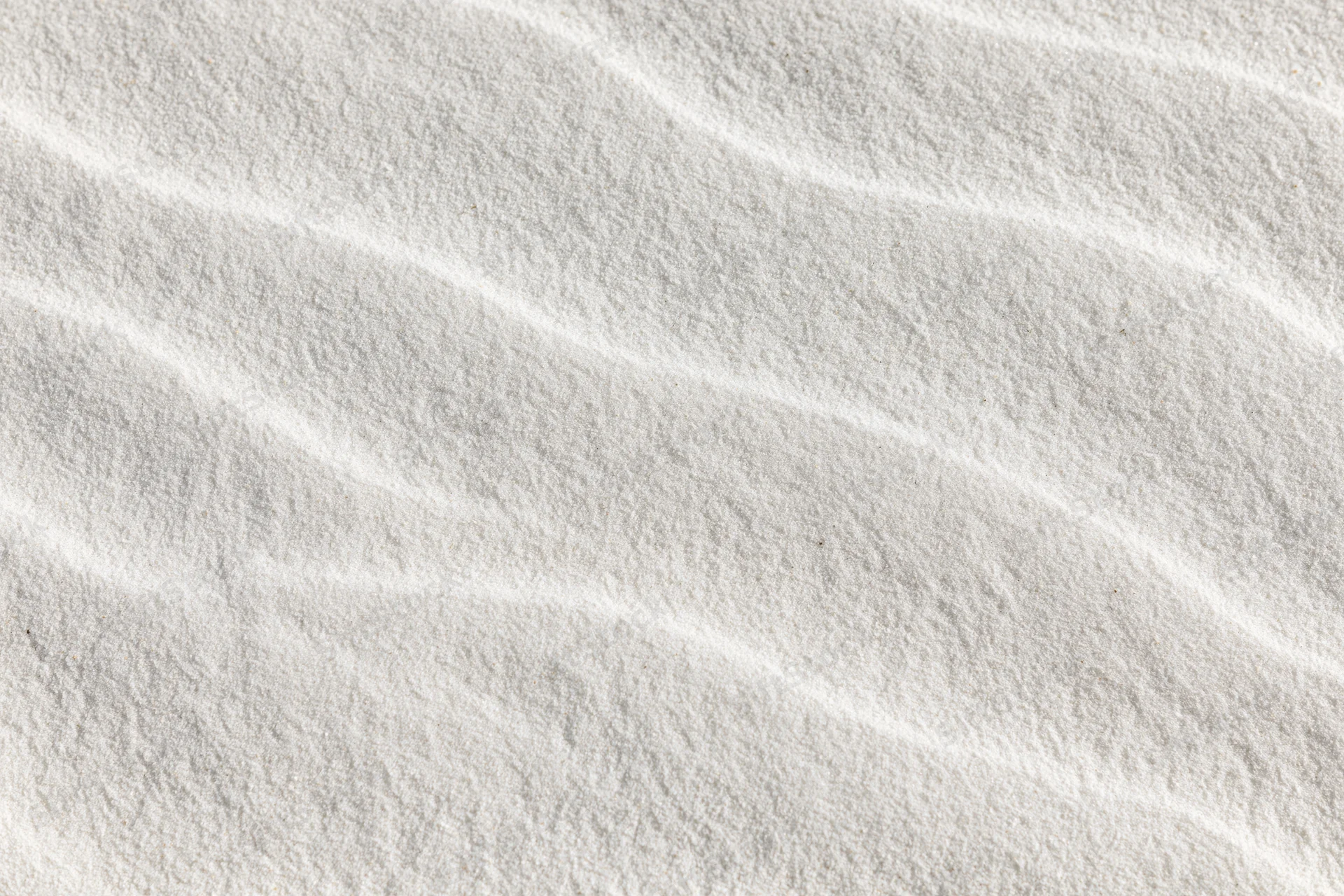Close-up of fine white beach sand with wind-formed ripples in a flat lay arrangement
