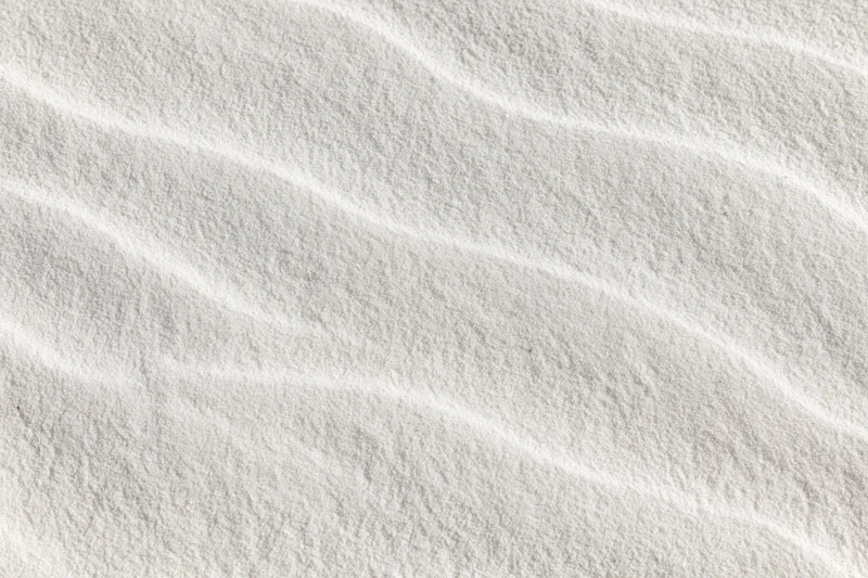 Close-up of fine white beach sand with wind-formed ripples in a flat lay arrangement