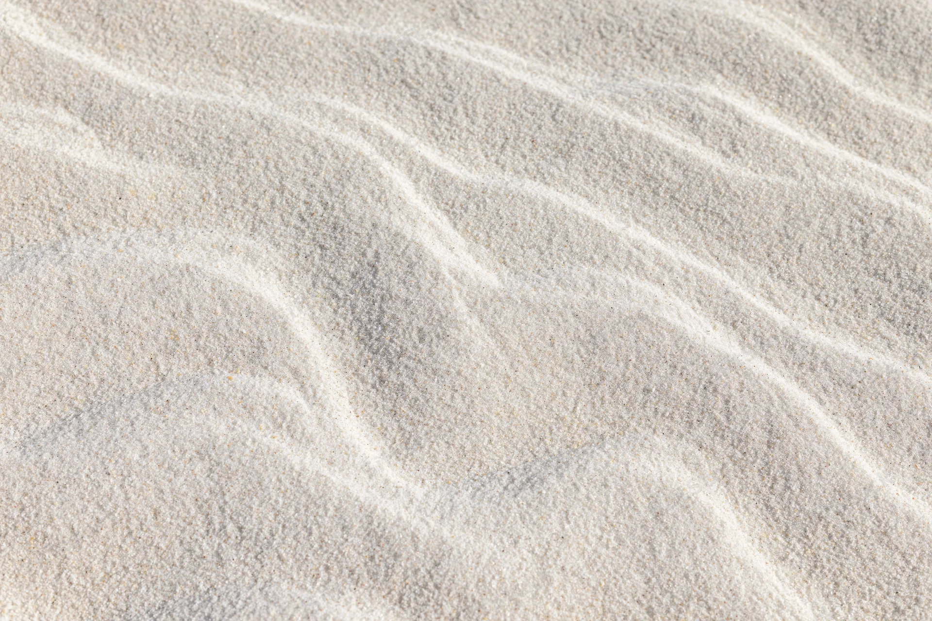 Close-up of fine white beach sand with wind-formed ripples across the surface