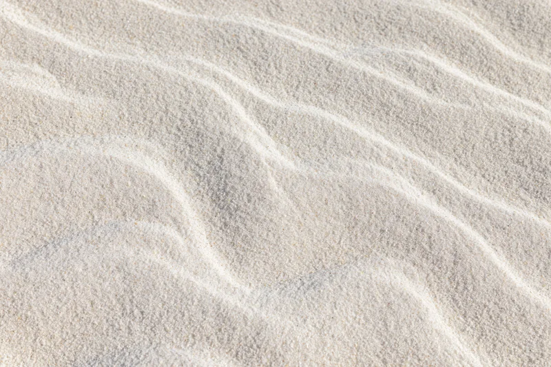 Close-up of fine white beach sand with wind-formed ripples across the surface