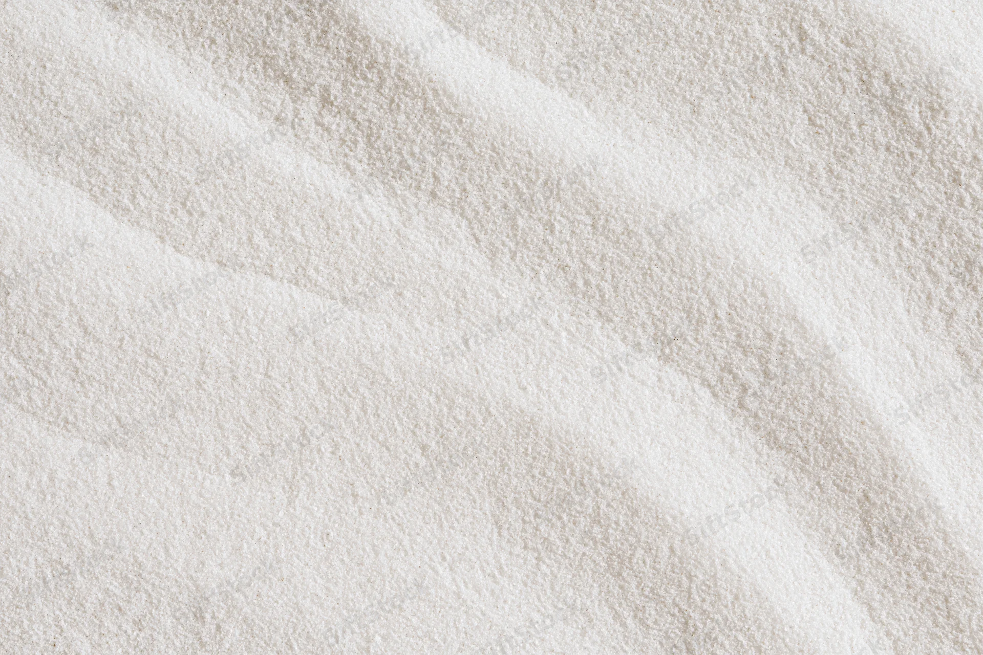 Close-up of fine white sand with smooth raked wave patterns in a flat lay arrangement